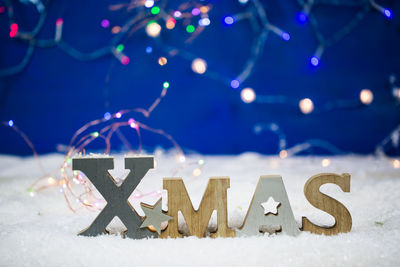 Close-up of illuminated christmas sign on snow