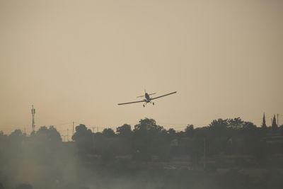 Low angle view of airplane flying against sky during sunset