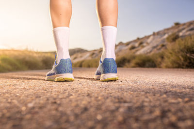 Low section of woman wearing shoes and socks while standing on road