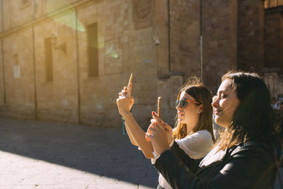 Two women tourist visiting an ancient city in spain taking a picture of a salamanca monument 