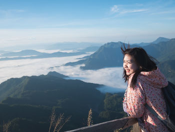 Smiling woman standing on mountain against sky