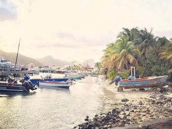 Boats in sea against cloudy sky