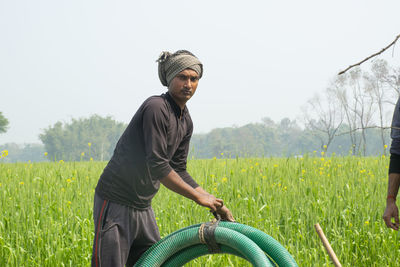 Indian farmer holding water pipe in the field