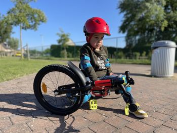 Young boy of four with disappointed face by learning bicycle on street