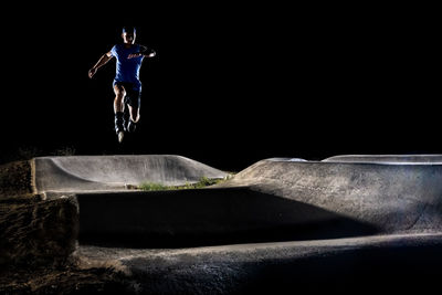 Man wearing inline skates jumping at skateboard park