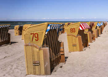 Hooded chairs at beach against sky