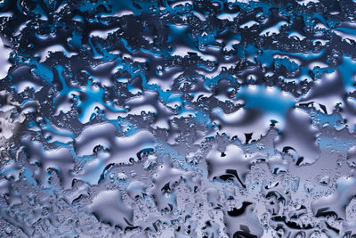 Full frame shot of wet glass, water on a glass plate forming abstract patterns
