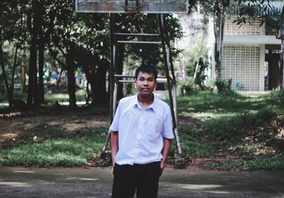 Portrait of young man standing against trees