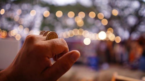 Close-up of hand holding illuminated blurred lights