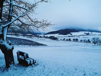 Snow covered field against sky during winter