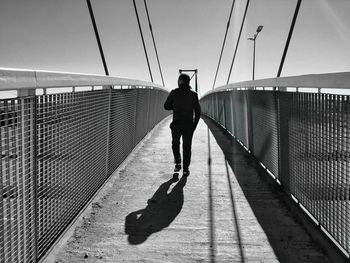 Rear view of man standing on footbridge