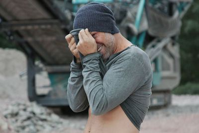 Portrait of man hiding behind his shirt