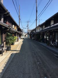 Road by railroad tracks in city against clear sky