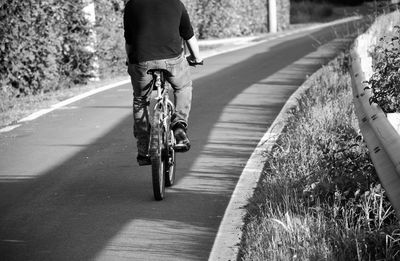 Rear view of man riding bicycle on road