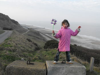 Girl playing with pinwheel against sea