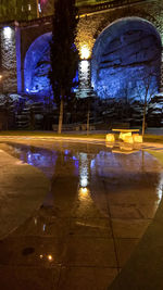 Reflection of illuminated building in puddle at night