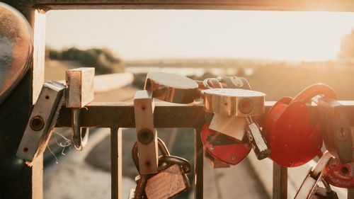 Close-up of padlocks hanging on metal fence against sky