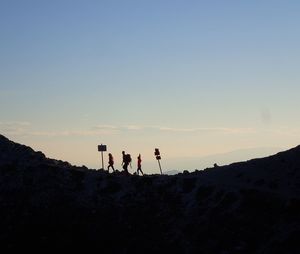 Silhouette people standing on mountain against sky during sunset