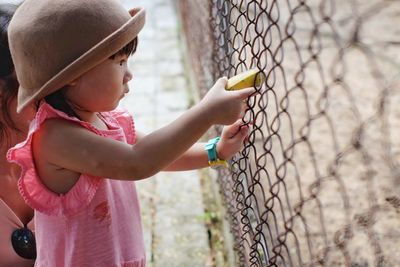 Side view of girl holding banana at zoo