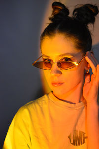 Portrait of young woman wearing sunglasses against black background