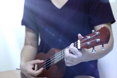 Close-up of man playing ukulele at home