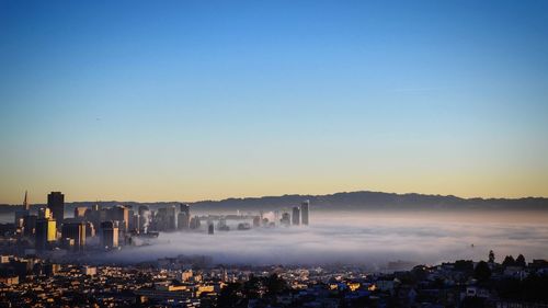 Wide angle view of cityscape covered with fog during sunset