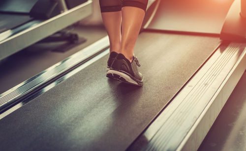 Low section of woman standing on escalator