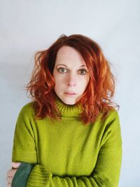 Portrait of mid adult woman with redhead standing against wall at home