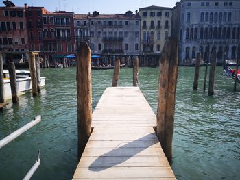 Wooden posts in canal amidst buildings in city