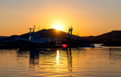 Boats moored in sea against sky during sunset