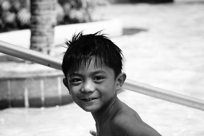 Portrait of wet smiling boy by swimming pool at resort