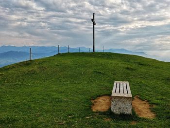 Seat and cross on mountain against sky