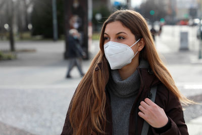 Young woman wearing mask while looking away in city