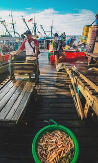 People working on boat against sky