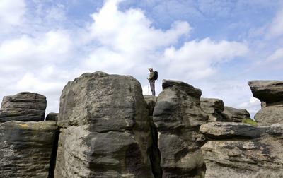 Rear view of man standing on rock against sky