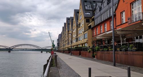 Bridge over river by buildings against sky