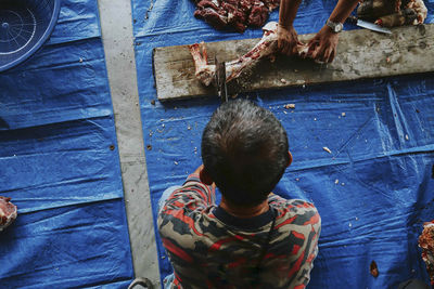 Rear view of man cutting meat in shop