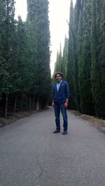 Full length of man standing on road amidst trees