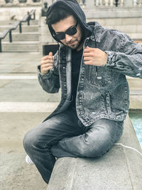 Young man wearing sunglasses sitting outdoors