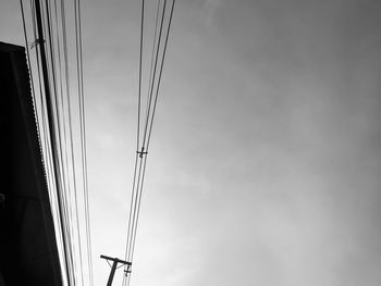 Low angle view of silhouette electricity pylon against sky