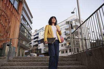 Low angle view of woman walking down stairs and carrying skateboard