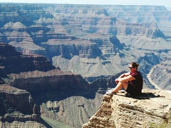 Full length of woman sitting on cliff