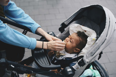 Cropped image of mother holding pacifier on baby's mouth at sidewalk