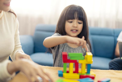 Mother and daughter playing with toy blocks at home