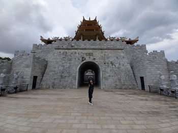 Woman walking in historic building against sky