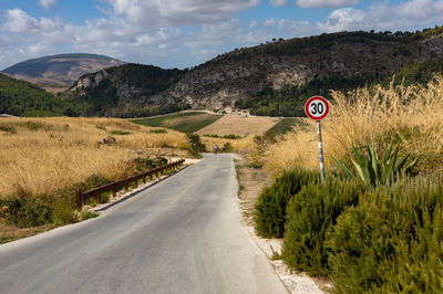 Road leading towards mountains against sky