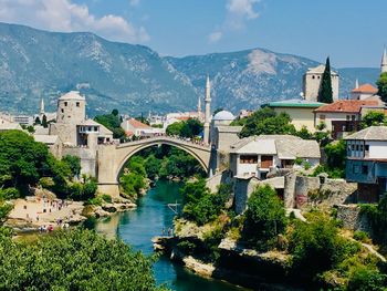 Arch bridge over river amidst buildings in city