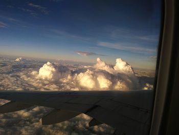 Aerial view of airplane wing over clouds seen through window
