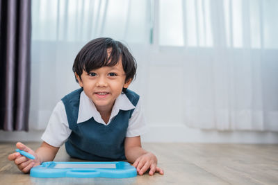 Portrait of cute boy writing on slate while lying on floor