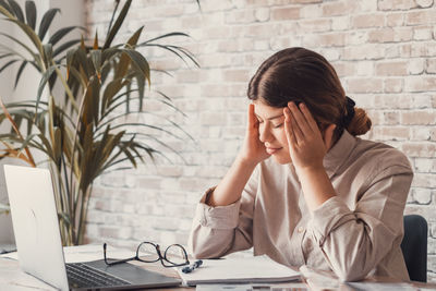 Side view of young woman using laptop on table